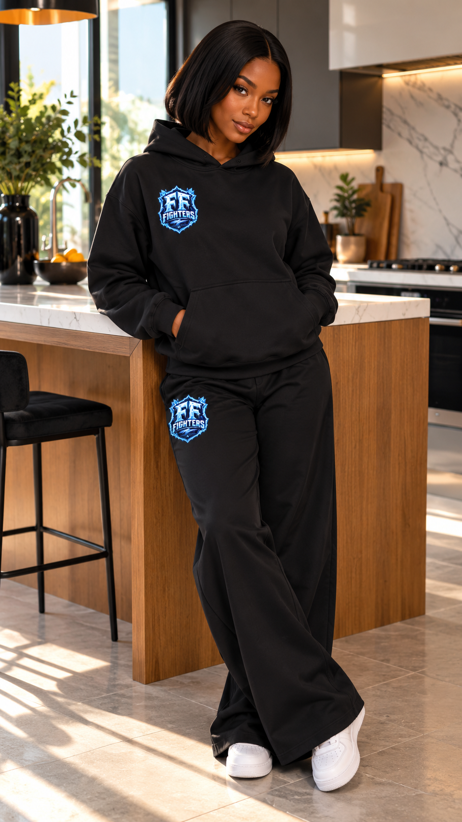Femme dans une cuisine portant le hoodie noir et le pantalon noir Fruits Fighters avec logo
